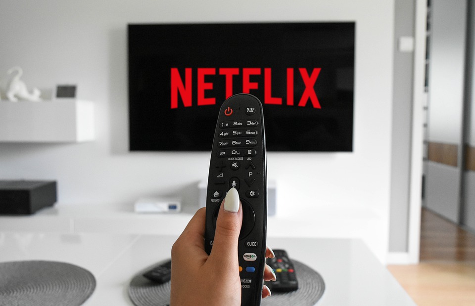 Person holding TV remote showing Netflix screen